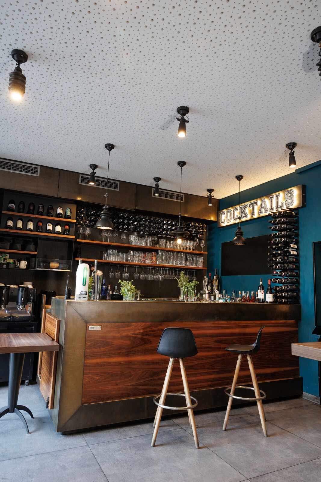Il bancone in legno con gli sgabelli, sotto l'insegna Cocktails