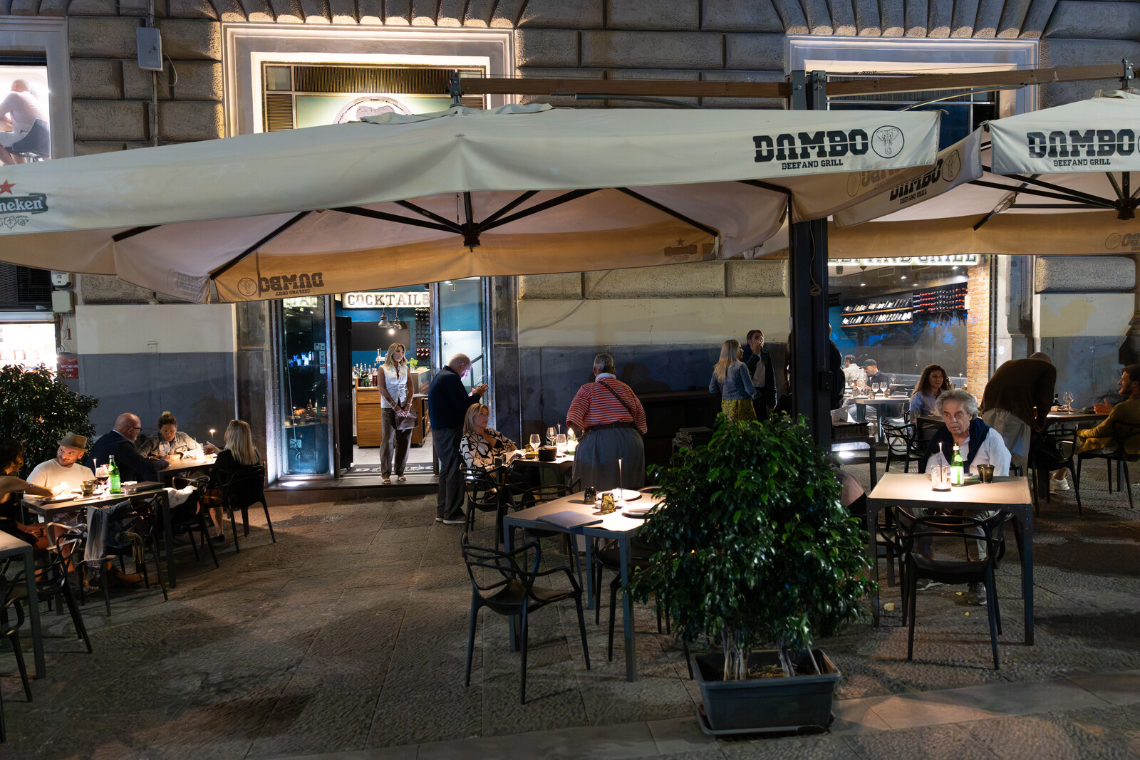 La facciata di Dambo di sera, con il dehors apparecchiato e le candele accese sui tavoli sotto gli ombrelloni