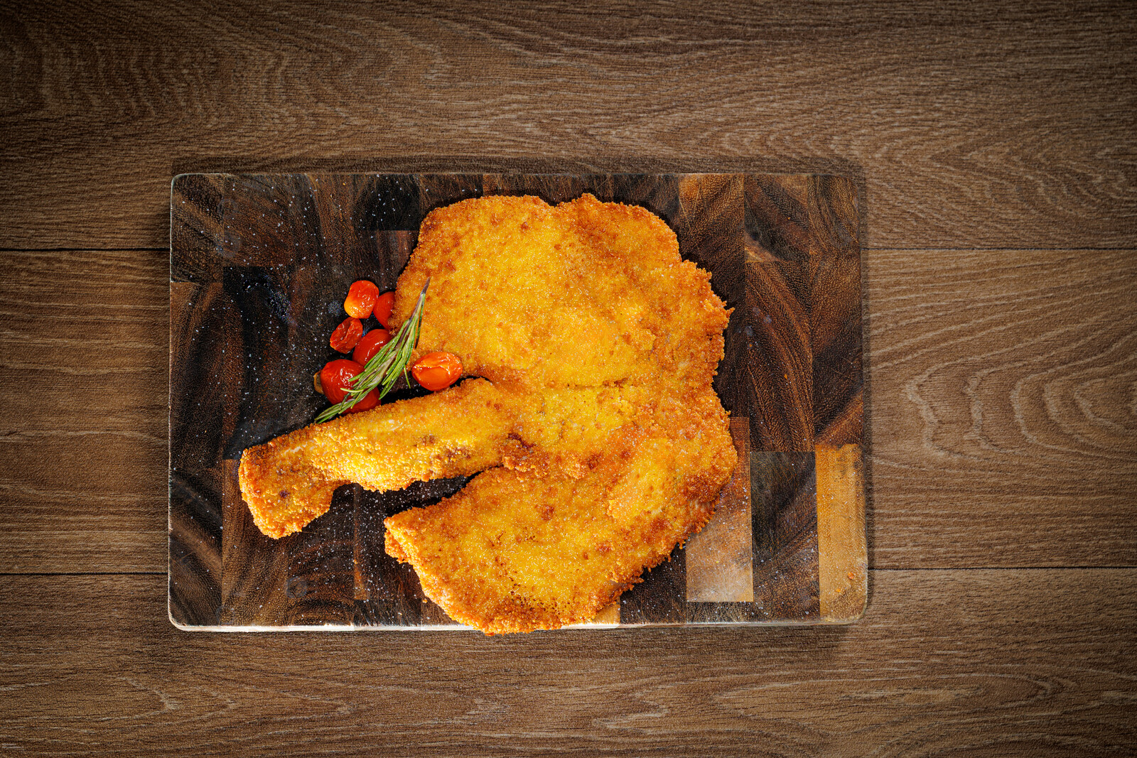 Cotoletta impanata dorata su tagliere di legno