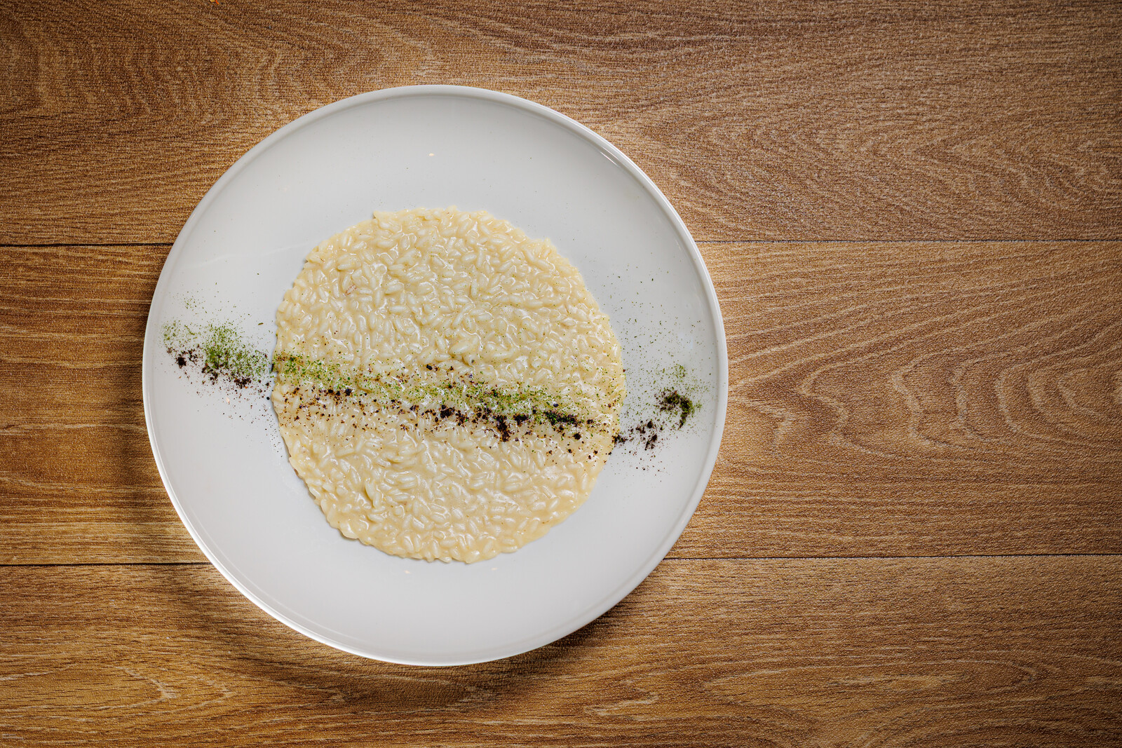 Disco di risotto con riga di salsa verde su piatto bianco