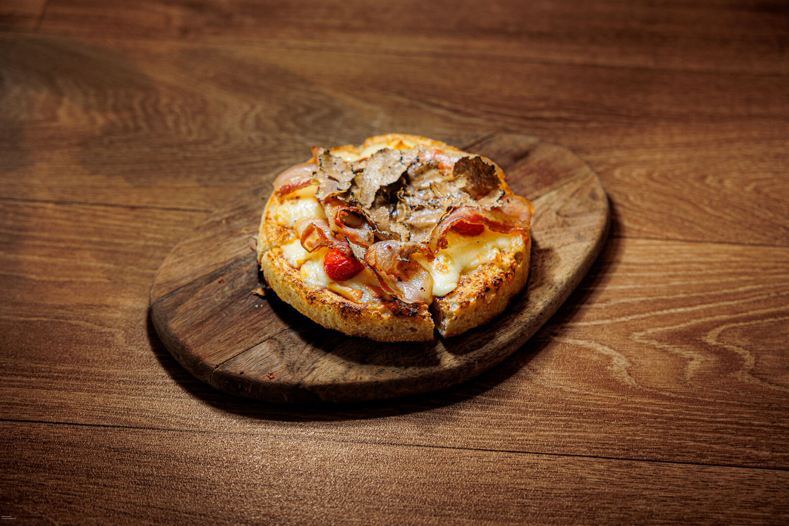Focaccia tonda con funghi e formaggio su tagliere di legno