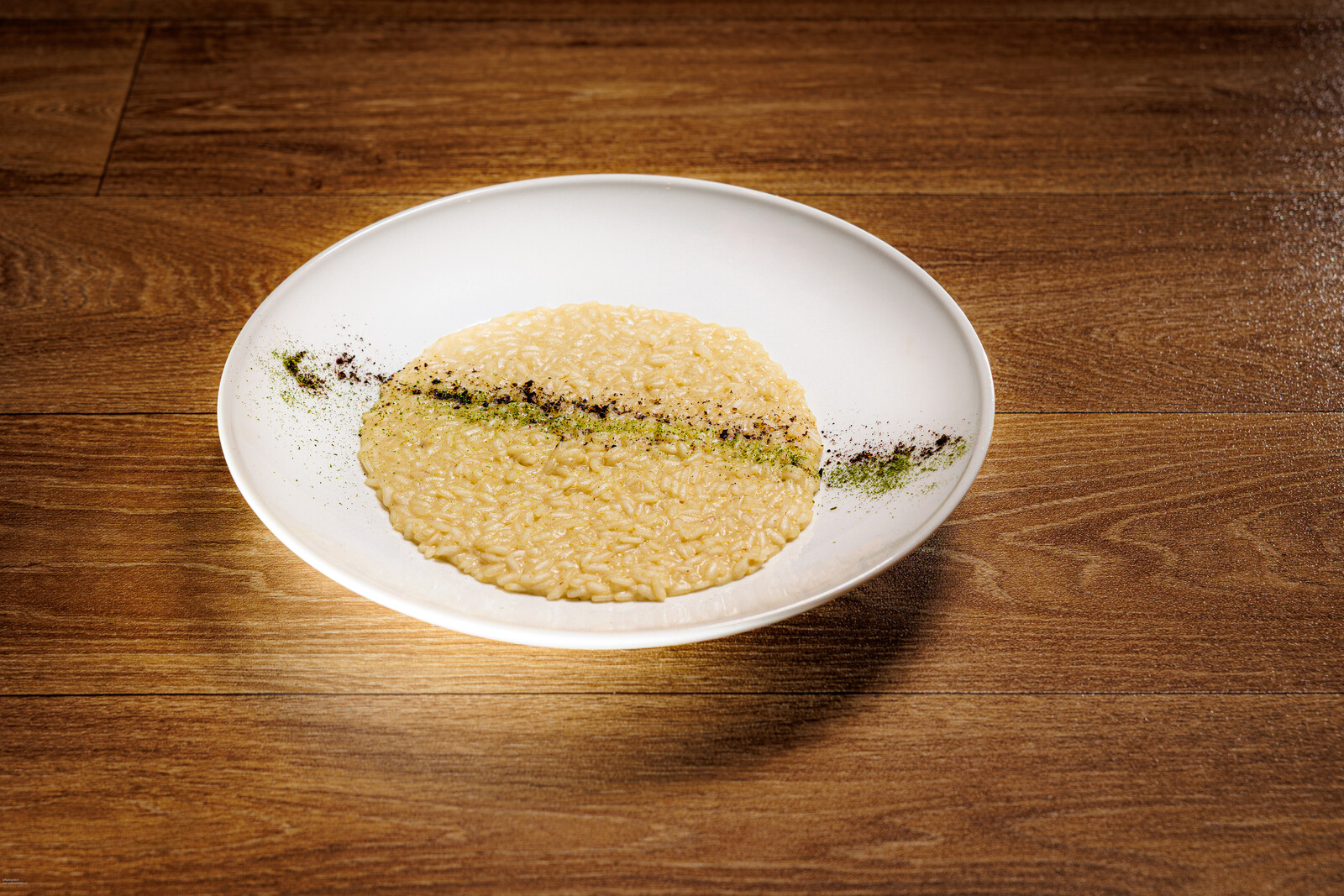 Piatto bianco con crema chiara e una riga di erbe