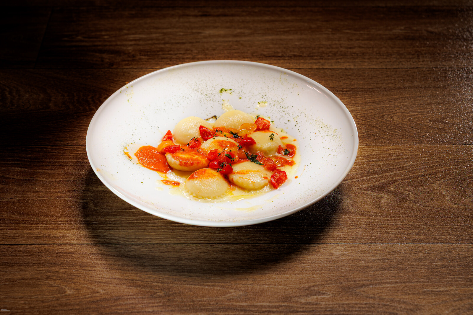 Piatto con fagottini di pasta, pomodorini e crema
