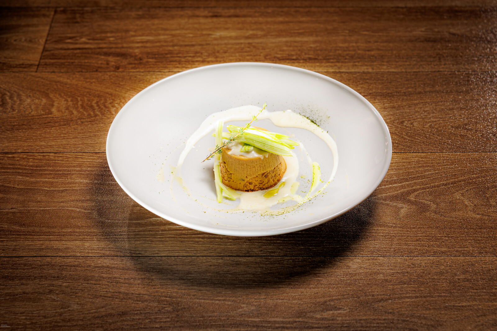 Tortino dorato con salsa bianca e listarelle di verdura su piatto fondo