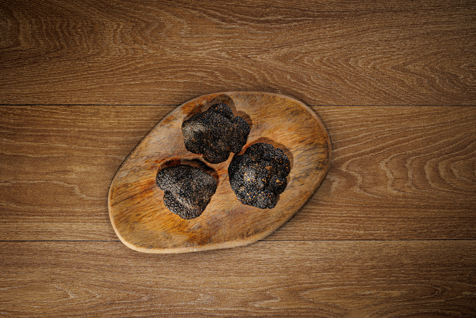 Tre tartufi neri su un piccolo tagliere di legno